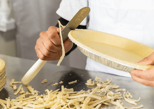 A chef cutting crust off of a pie