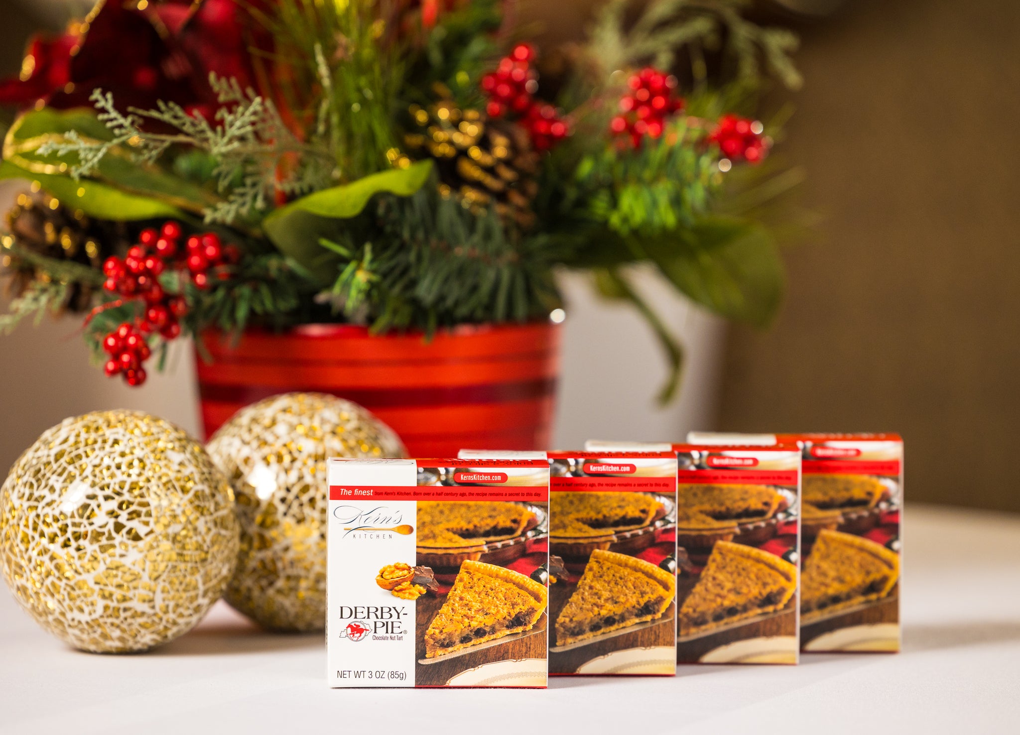 4 Mini Derby-Pie® chocolate nut tarts lined up next to each other with a Christmas background